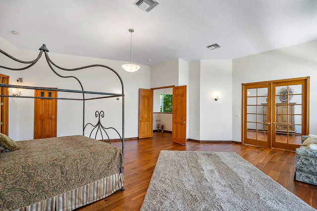 a bedroom with a bed and dresser with wooden floor