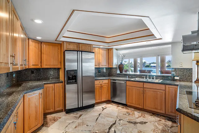a kitchen with stainless steel appliances granite countertop a sink a stove and refrigerator