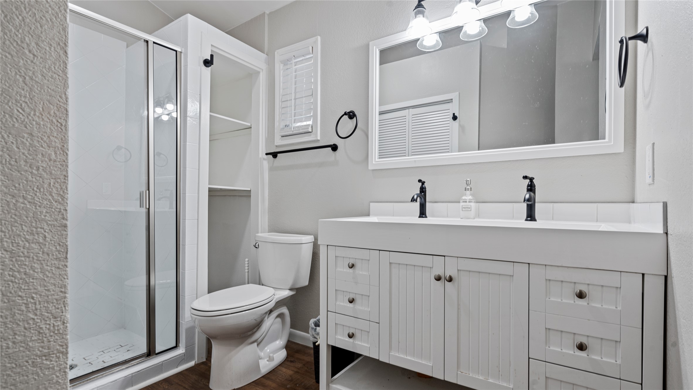 3108 Linnet Drive Austin, TX 78745 - Photo 11 of 24 Bathroom with double vanity, a shower stall, and dark wood-style flooring