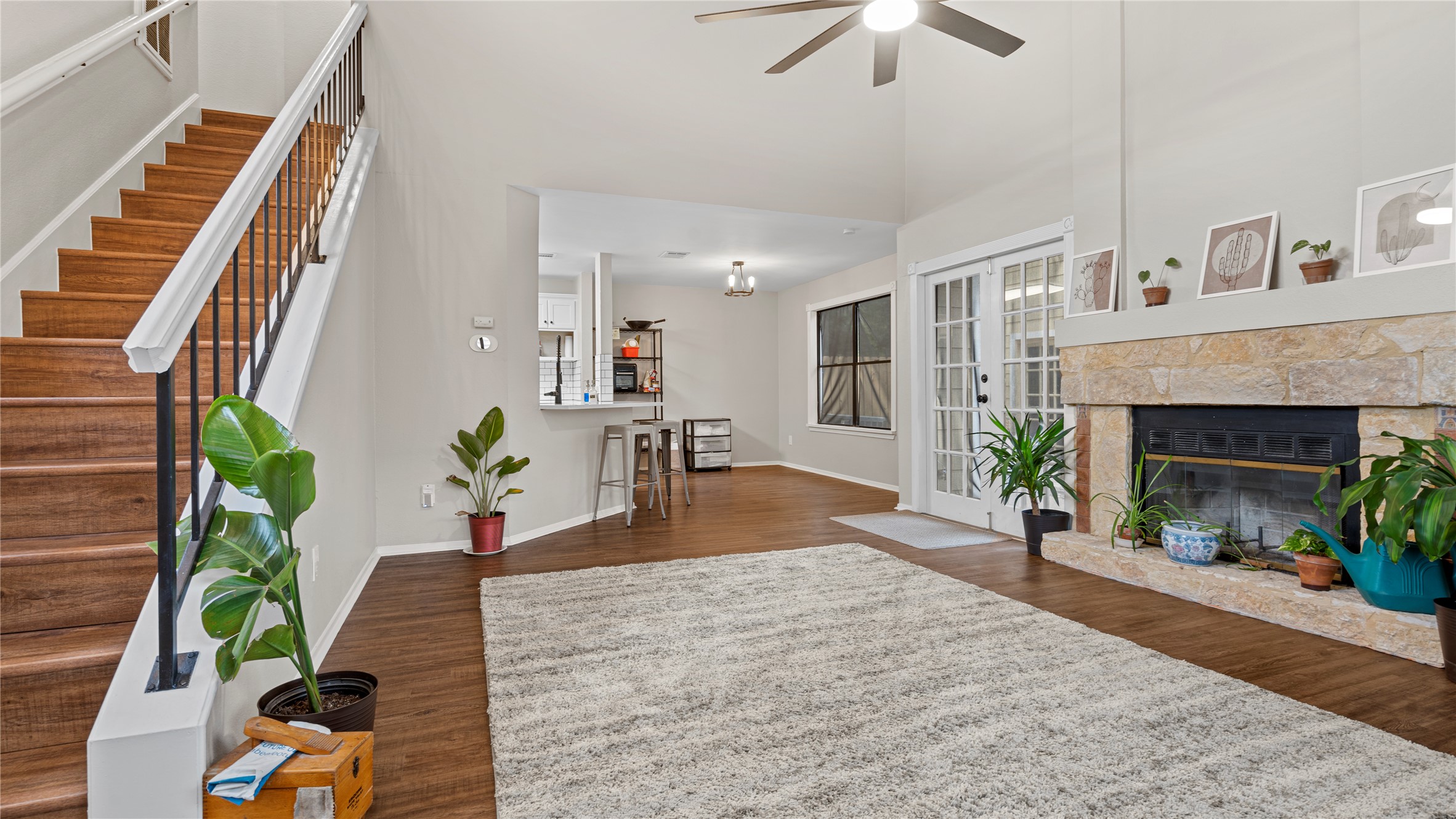 3108 Linnet Drive Austin, TX 78745 - Photo 15 of 24 Living room with a stone fireplace, dark wood-style flooring, a ceiling fan, a high ceiling, and plenty of natural light
