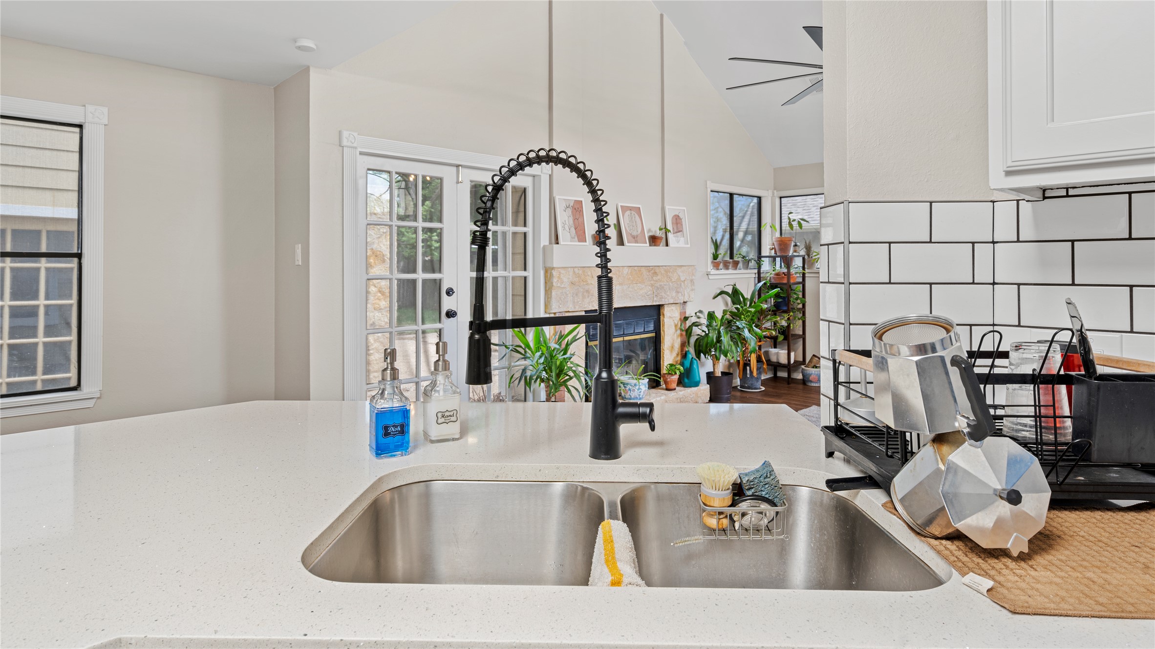 3108 Linnet Drive Austin, TX 78745 - Photo 16 of 24 Kitchen with light stone counters, vaulted ceiling, a glass covered fireplace, plenty of natural light, and tasteful backsplash