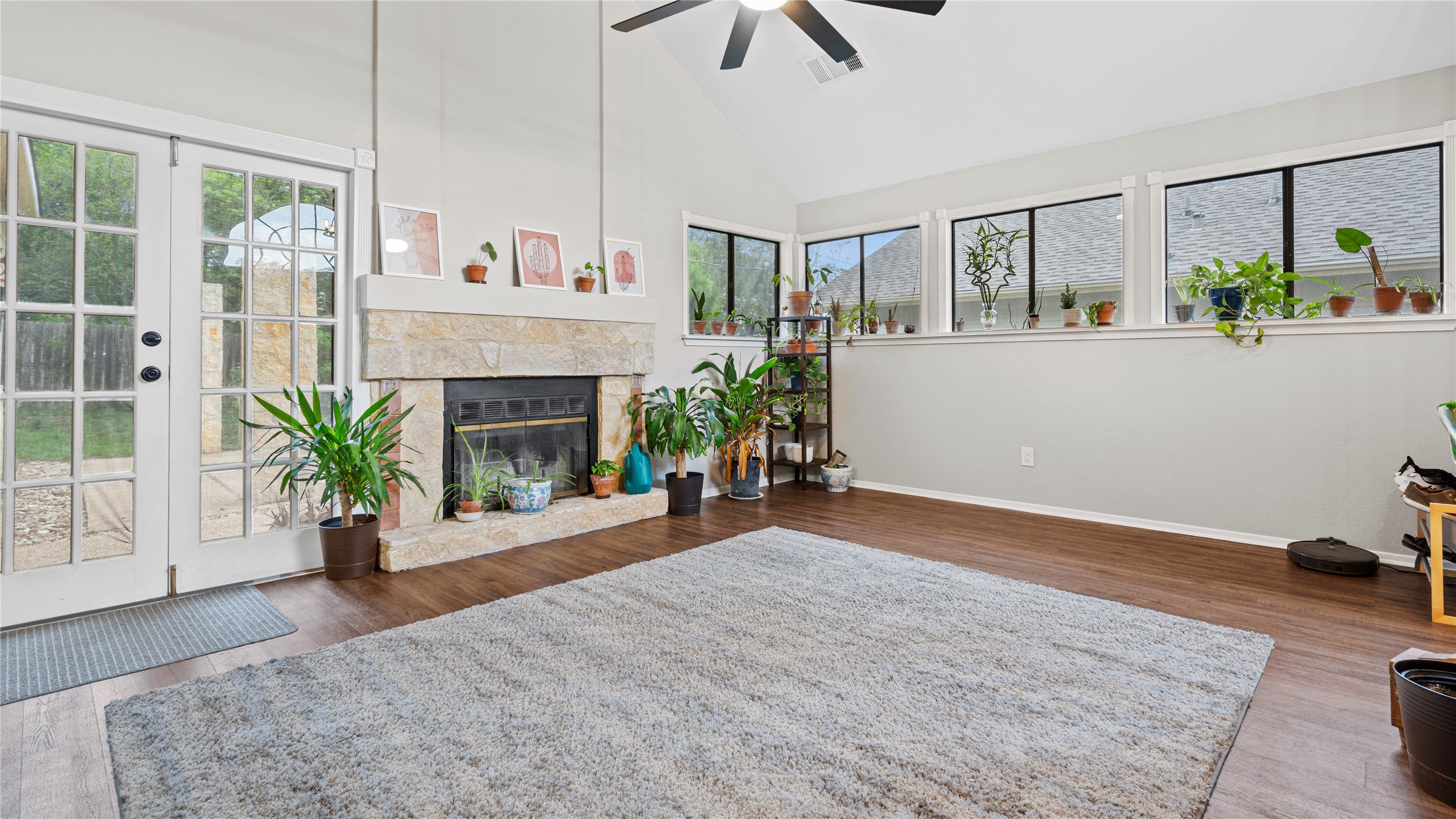 3108 Linnet Drive Austin, TX 78745 - Photo 20 of 24 Living area with dark wood-type flooring, vaulted ceiling, healthy amount of natural light, a stone fireplace, and ceiling fan