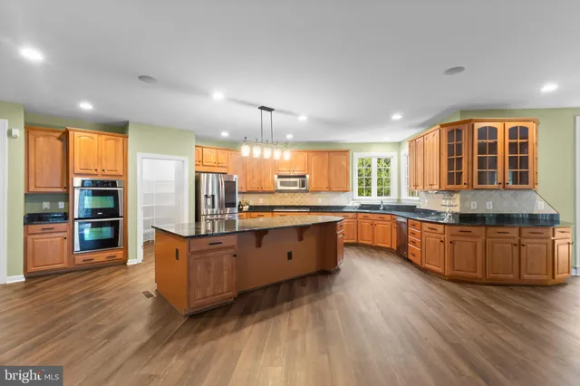 a spacious bathroom with a granite countertop sink a toilet a mirror and shower