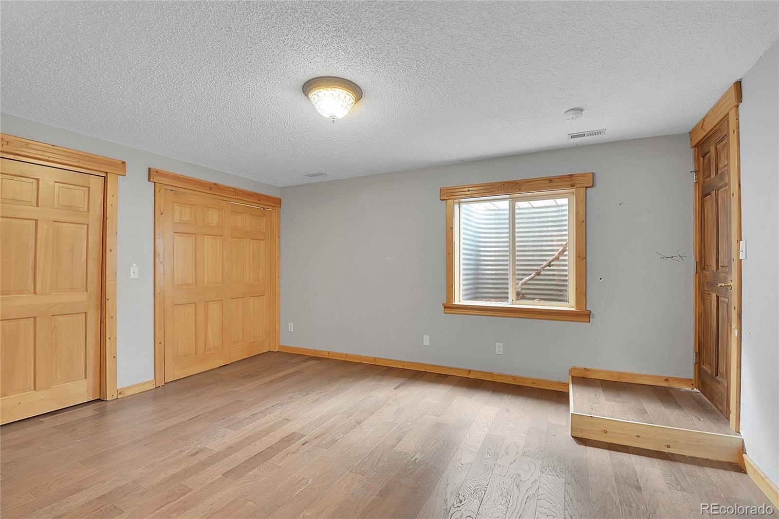 211 Chalet Drive Black Hawk, CO 80422 - Photo 21 of 36 an empty room with wooden floor and windows