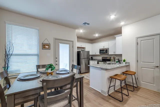 a kitchen with stainless steel appliances kitchen island granite countertop a dining table chairs and refrigerator