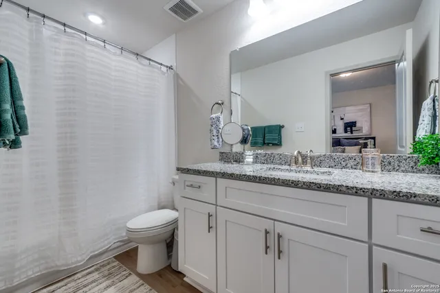 a bathroom with a granite countertop toilet sink and mirror