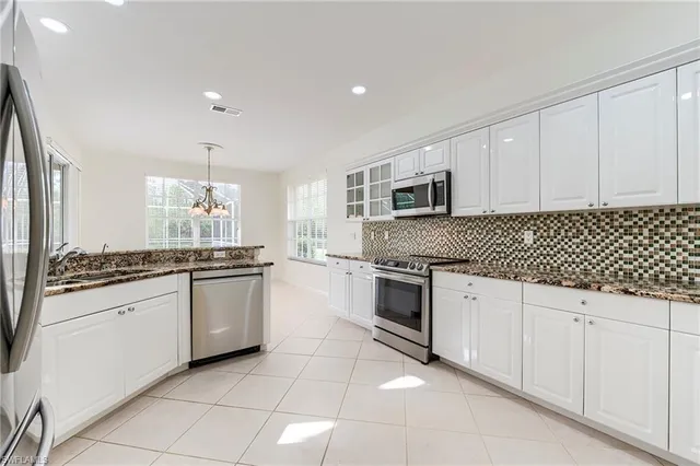 a kitchen with granite countertop white cabinets and stainless steel appliances
