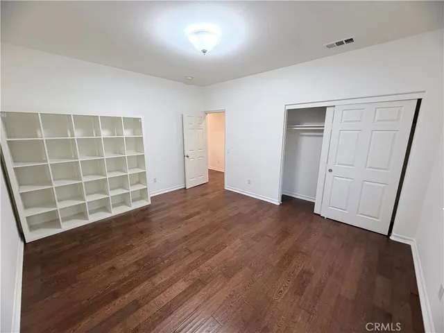 an empty room with wooden floor and cabinet