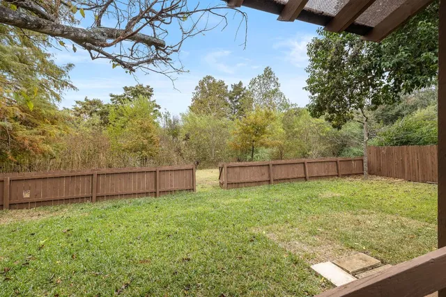 a view of a backyard with a tree and wooden fence