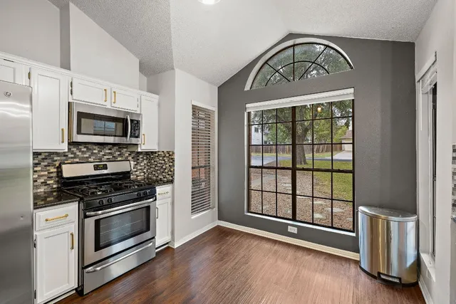a view of kitchen with granite countertop a stove top oven a sink and a window