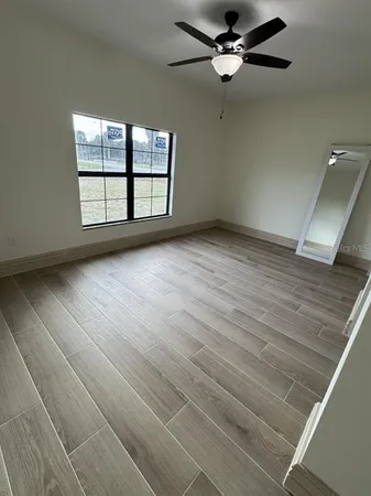 an empty room with windows and ceiling fan