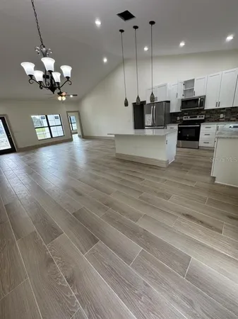 a view of a kitchen with granite countertop wooden floor stainless steel appliances and a couch