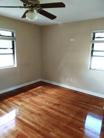 an empty room with wooden floor closet and windows