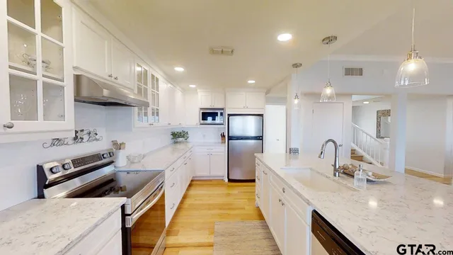 a large kitchen with stainless steel appliances kitchen island a large counter top a stove a sink and a refrigerator