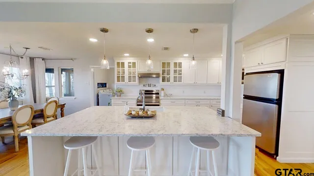 a kitchen with stainless steel appliances granite countertop a sink a refrigerator and a stove