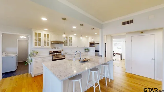a kitchen with stainless steel appliances kitchen island granite countertop a table and chairs in it