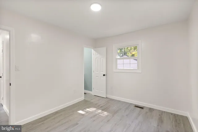 an empty room with wooden floor and window
