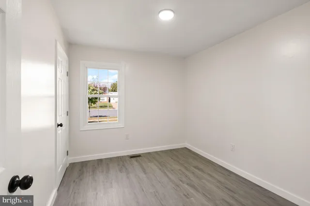 an empty room with a window and wooden floor