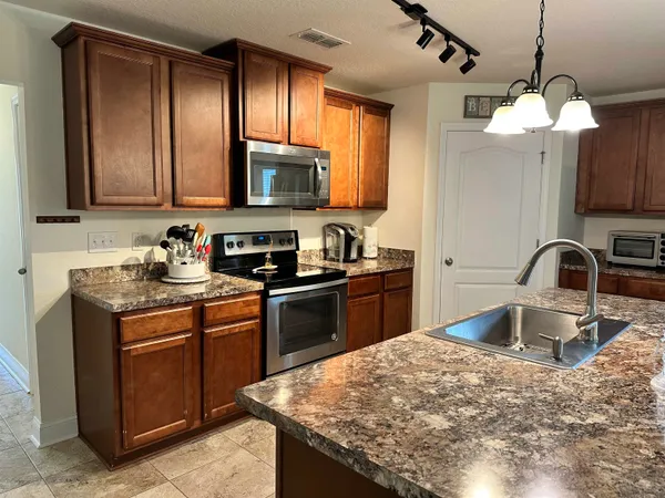 a kitchen with kitchen island granite countertop a sink stainless steel appliances and cabinets