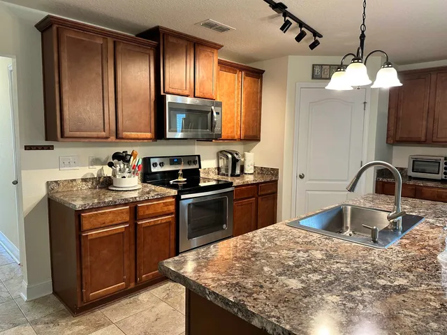 a kitchen with kitchen island granite countertop a sink stainless steel appliances and cabinets