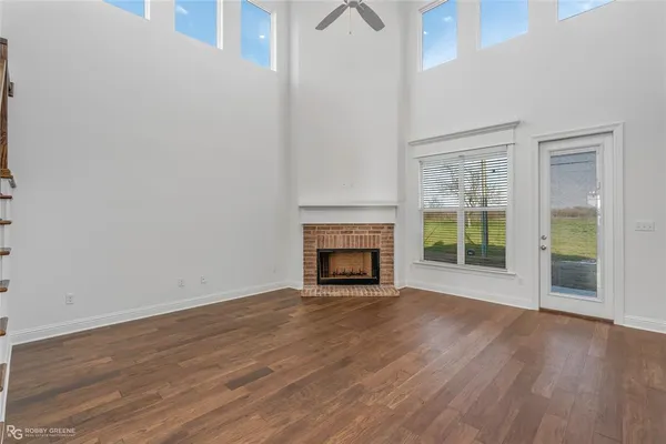an empty room with wooden floor fireplace and windows