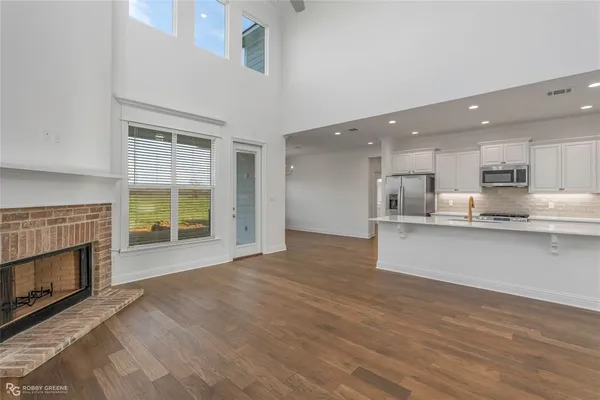 a view of kitchen with kitchen island wooden floor and stainless steel appliances