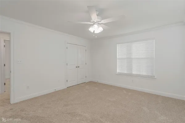 an empty room with a chandelier fan and windows