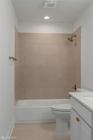 a bathroom with a granite countertop bathtub shower sink vanity and toilet