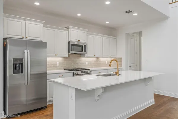 a kitchen with kitchen island a counter top space stainless steel appliances and cabinets