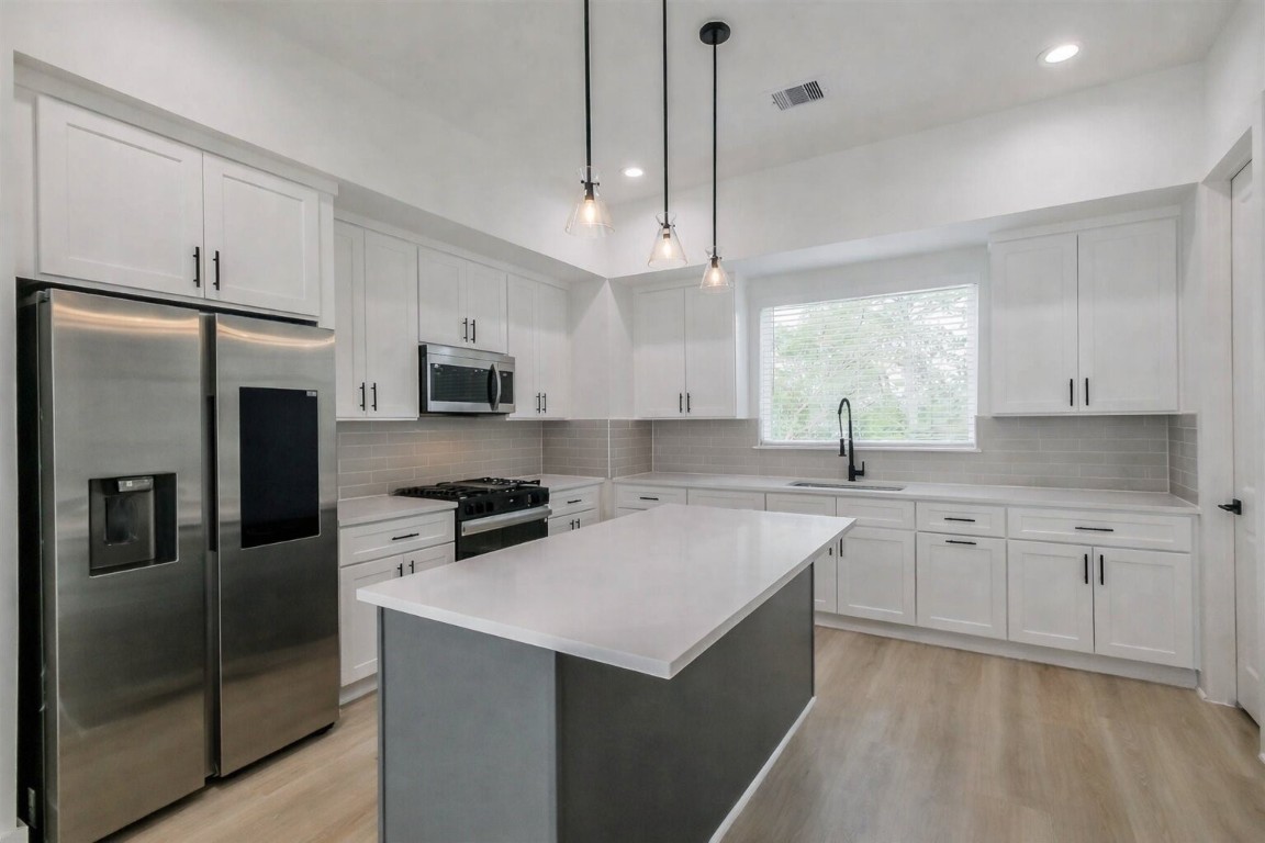 5703 Balbo Street, Unit F Houston, TX 77091 - Photo 13 of 39 a kitchen with a sink a center island a stove and a refrigerator
