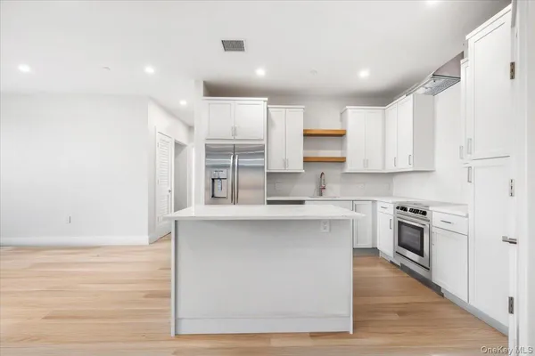 a kitchen with stainless steel appliances granite countertop a stove top oven a sink dishwasher and a refrigerator with wooden floor