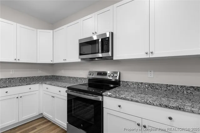 a kitchen with granite countertop white cabinets and refrigerator