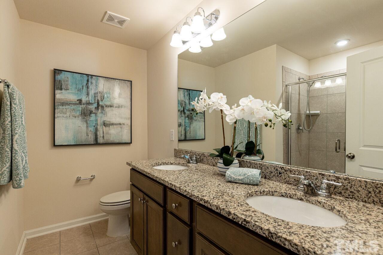 117 Lafferty Street Durham, NC 27560 - Photo 18 of 43 a bathroom with a granite countertop double vanity sink a mirror and a toilet