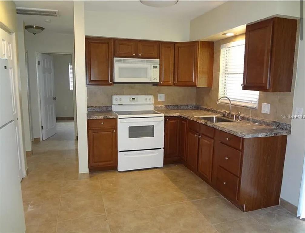 6439 Polk Street New Port Richey, FL 34653 - Photo 2 of 11 a kitchen with a stove top oven sink and cabinets