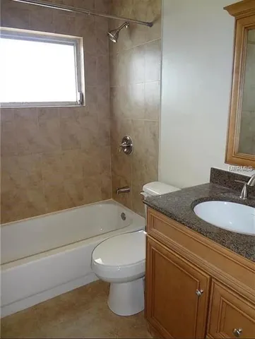 a bathroom with a granite countertop toilet a sink and bathtub
