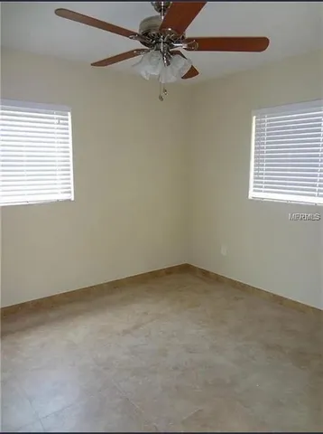 an empty room with a window and a fan