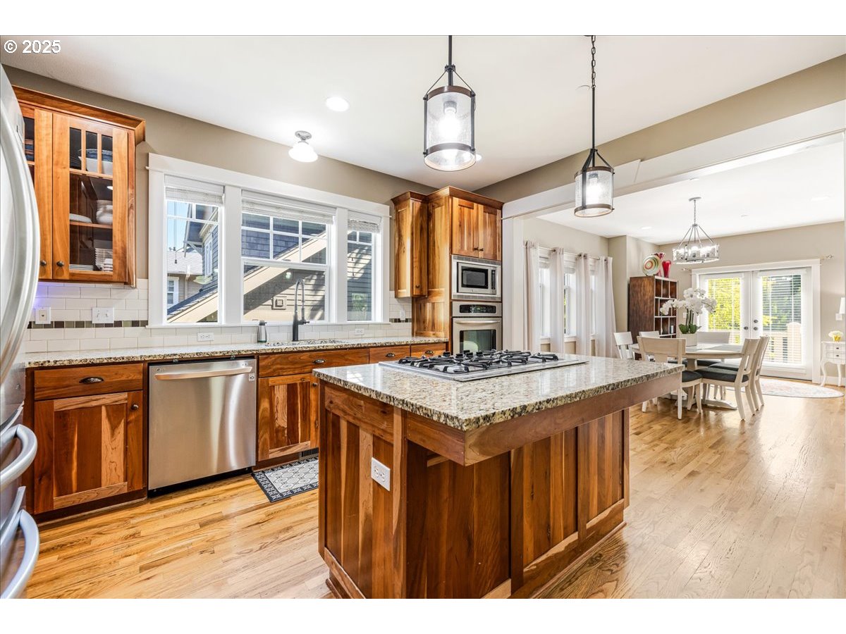 8250 Southwest Indigo Terrace Beaverton, OR 97007 - Photo 16 of 46 a kitchen with stainless steel appliances granite countertop wooden floors and white cabinets