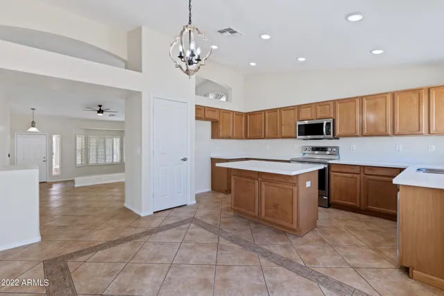 a kitchen with stainless steel appliances granite countertop a stove top oven a sink dishwasher and a refrigerator with wooden cabinets