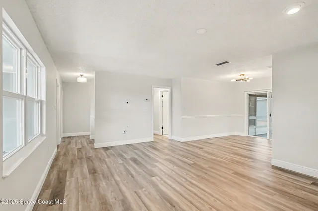 a view of empty room with wooden floor and windows