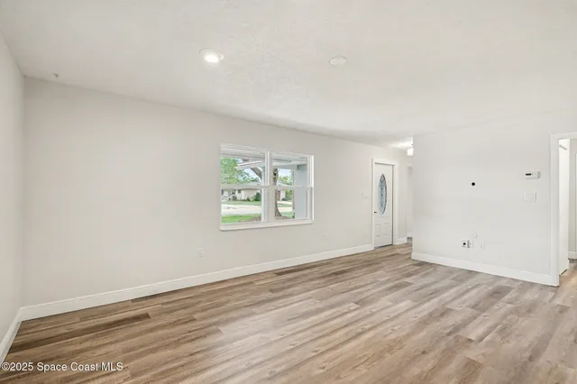 an empty room with wooden floor and window