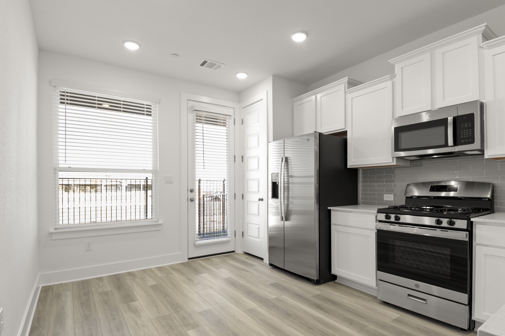 18909 Schultz Lane, Unit 1002 Round Rock, TX 78664 - Photo 10 of 24 Kitchen featuring appliances with stainless steel finishes, white cabinetry, light wood finished floors, backsplash, and recessed lighting