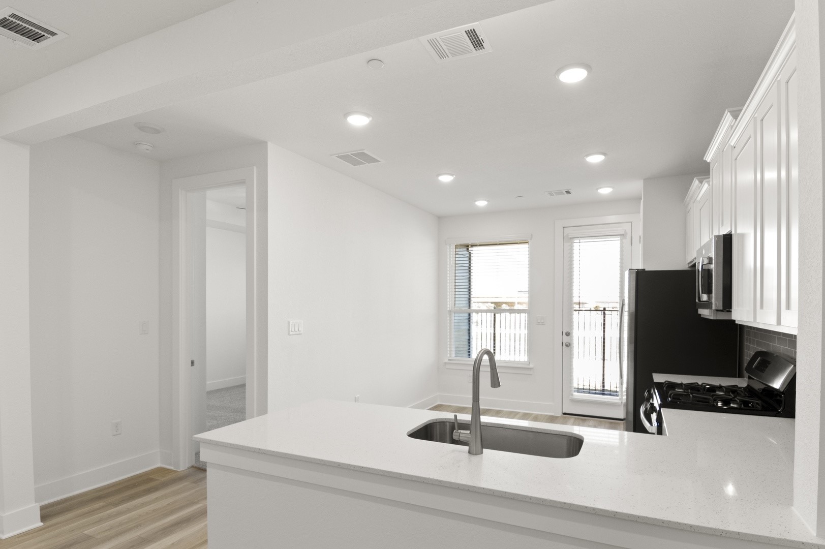 18909 Schultz Lane, Unit 1002 Round Rock, TX 78664 - Photo 12 of 24 Kitchen featuring a peninsula, light stone counters, white cabinetry, stainless steel appliances, and light wood-style floors