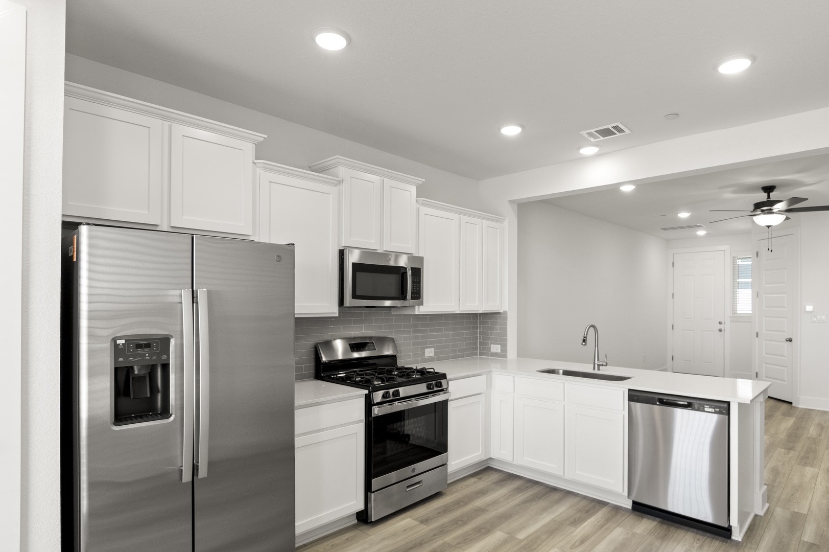 18909 Schultz Lane, Unit 1002 Round Rock, TX 78664 - Photo 14 of 24 Kitchen featuring stainless steel appliances, white cabinetry, light wood-type flooring, recessed lighting, and decorative backsplash