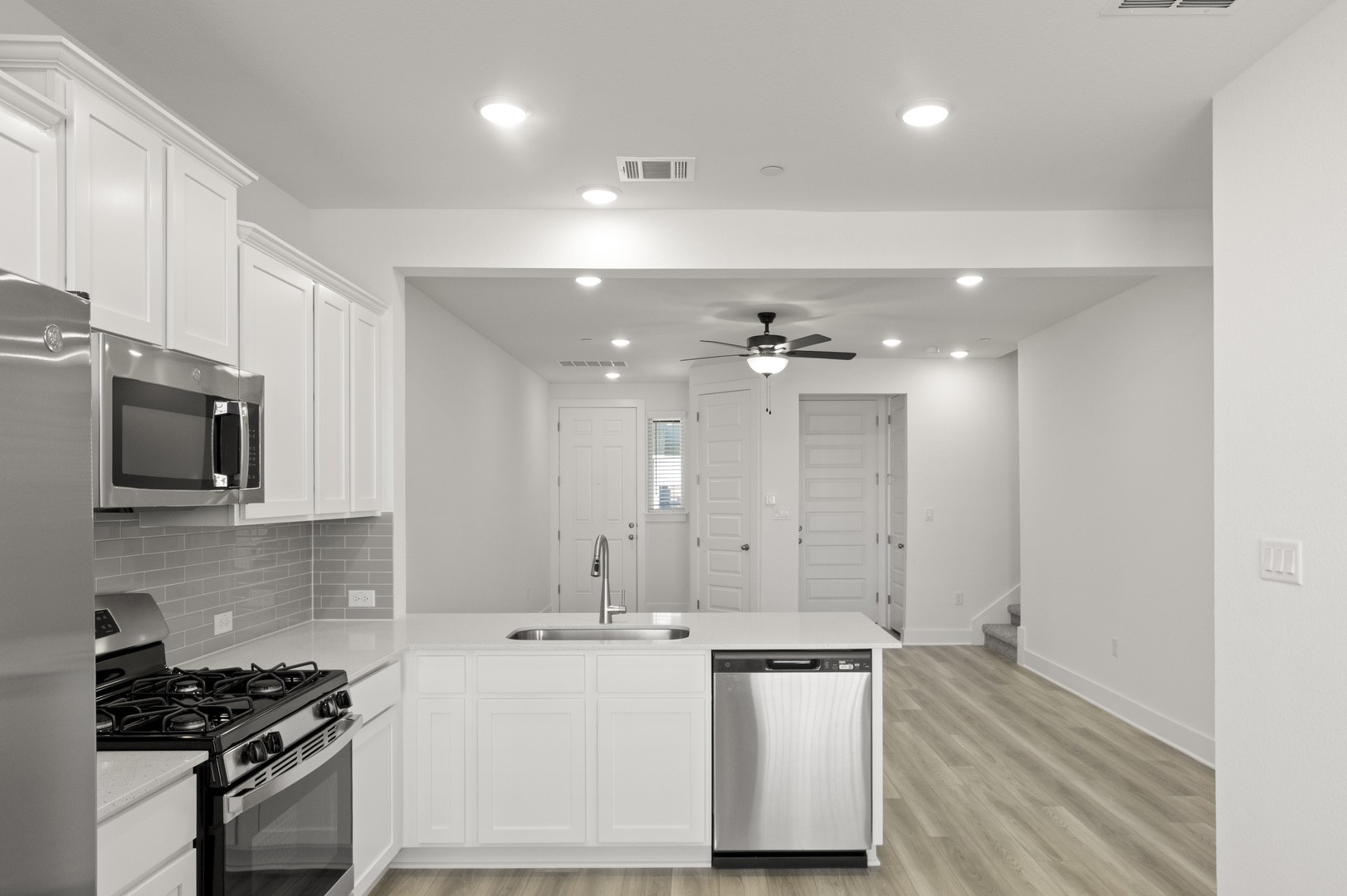 18909 Schultz Lane, Unit 1002 Round Rock, TX 78664 - Photo 15 of 24 Kitchen featuring appliances with stainless steel finishes, white cabinets, a peninsula, backsplash, and ceiling fan