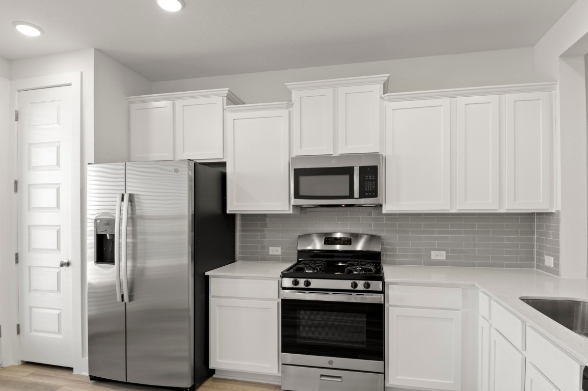 18909 Schultz Lane, Unit 1002 Round Rock, TX 78664 - Photo 16 of 24 a kitchen with stainless steel appliances granite countertop white cabinets a refrigerator a stove a sink and white cabinets