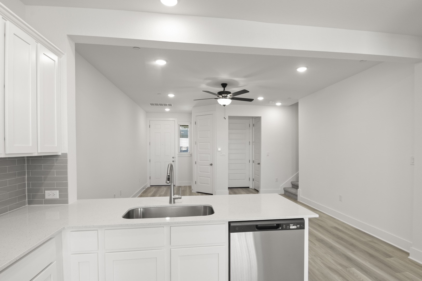 18909 Schultz Lane, Unit 1002 Round Rock, TX 78664 - Photo 17 of 24 Kitchen featuring dishwasher, white cabinets, light stone countertops, ceiling fan, and a peninsula