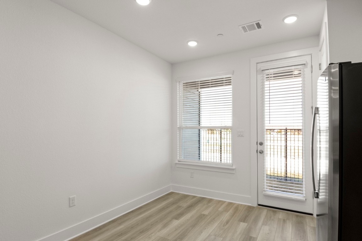 18909 Schultz Lane, Unit 1002 Round Rock, TX 78664 - Photo 9 of 24 an empty room with wooden floor and windows