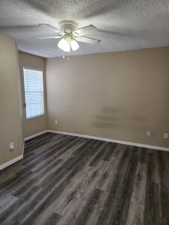 a view of an empty room with wooden floor and a chandelier fan