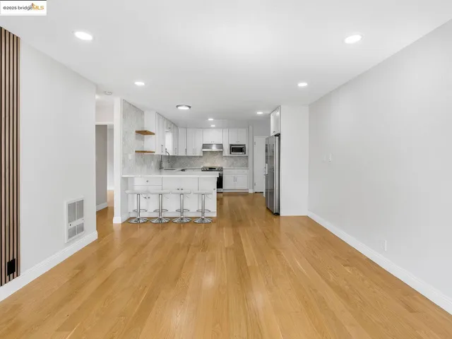 a view of kitchen with kitchen island a sink wooden floor and a refrigerator