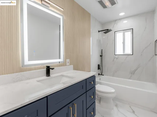 a bathroom with a granite countertop sink toilet a mirror and shower